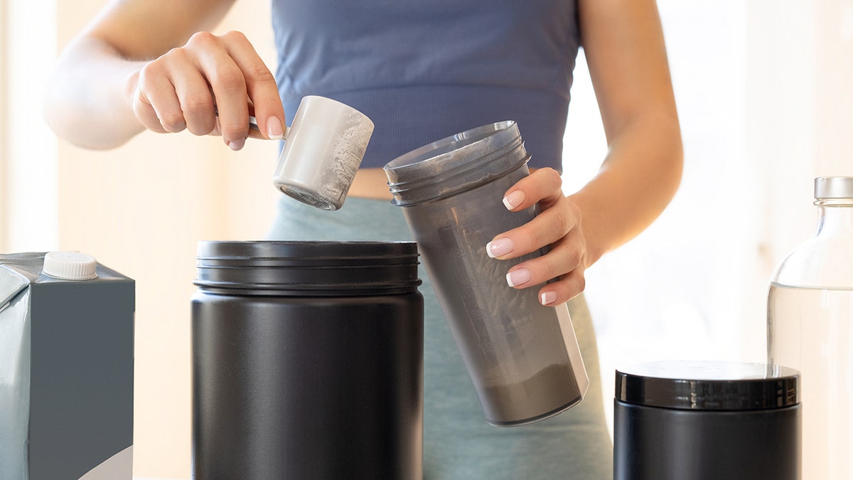 Close the shot of two hands preparing a kind of protein shaking in a gray container.