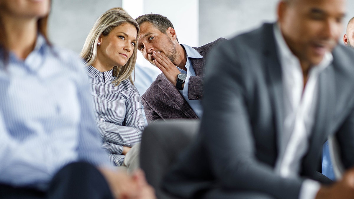 Businessman listening to her partner tells you a secret at a meeting