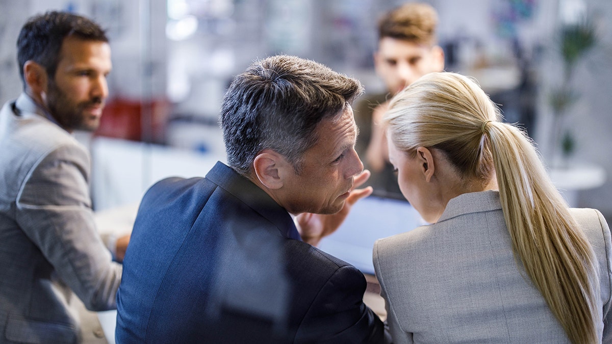 Fellows whisper and gossip during a business meeting