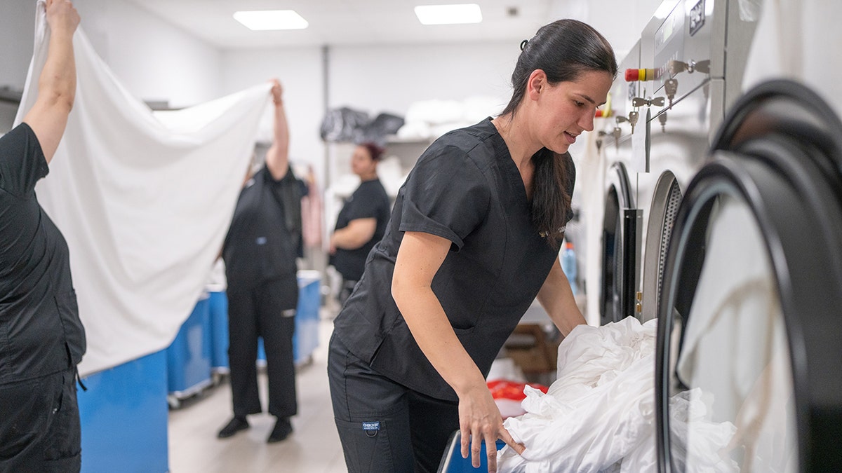 The woman washes her clothes in an industrial washing machine