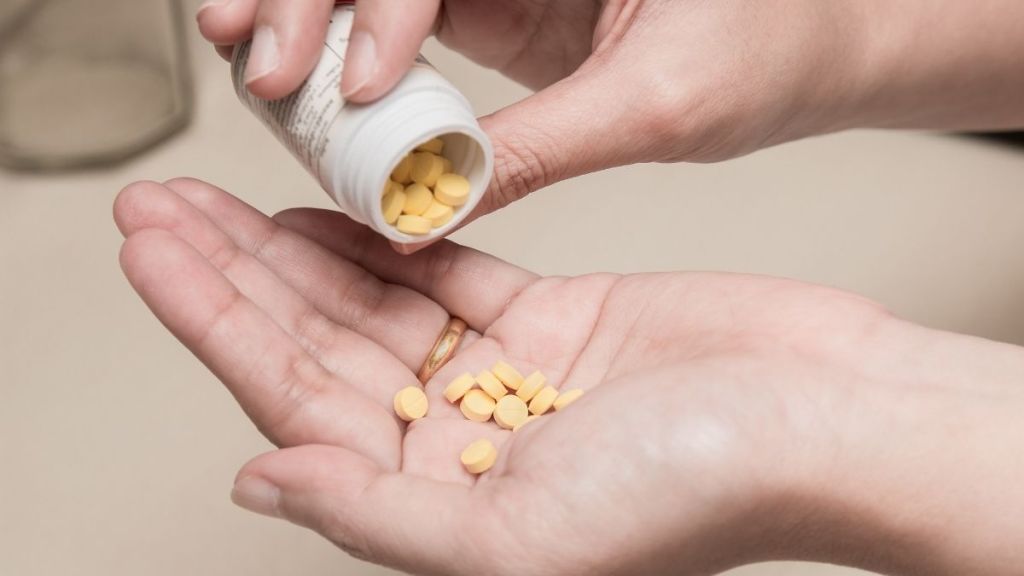 Woman holding a bottle of medication and pour some pills to another hand for medication for treatment