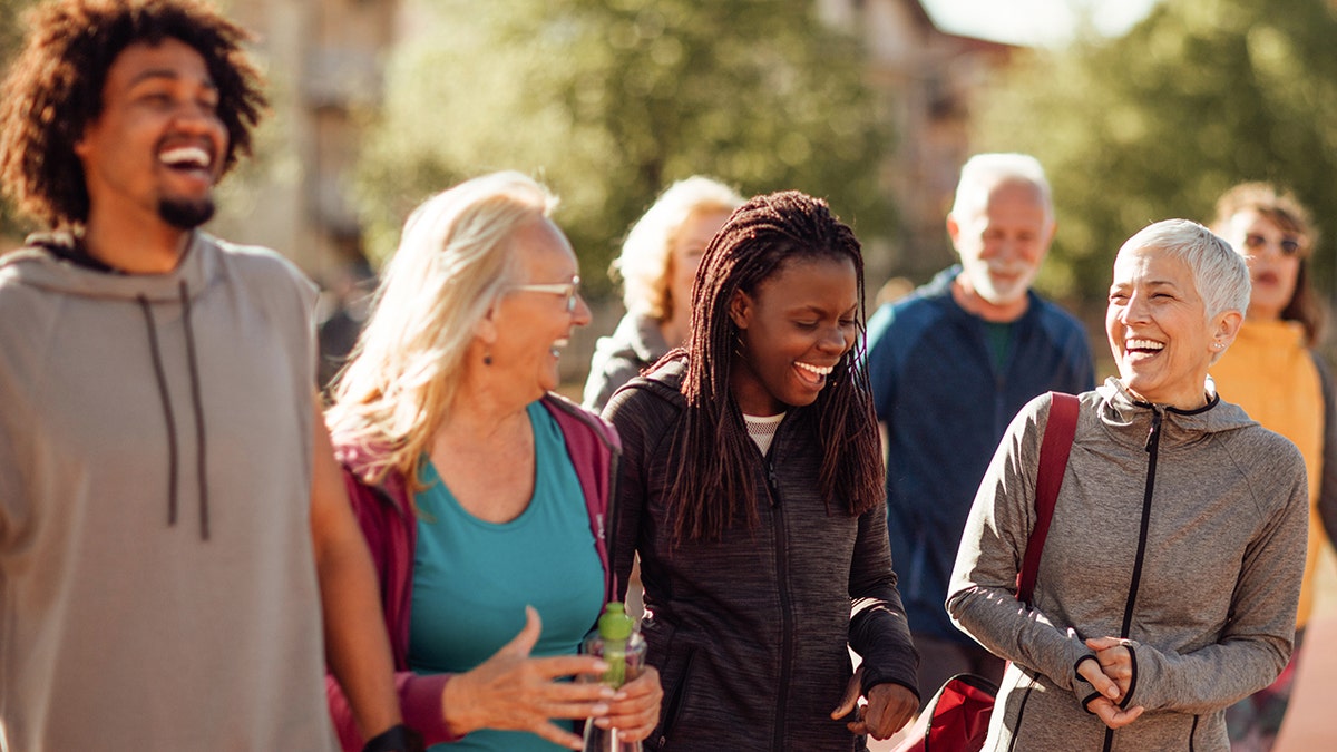 Smiling group of people walking together outdoors. A study shows that facing hearing loss can be a step in the right direction to combat senior loneliness