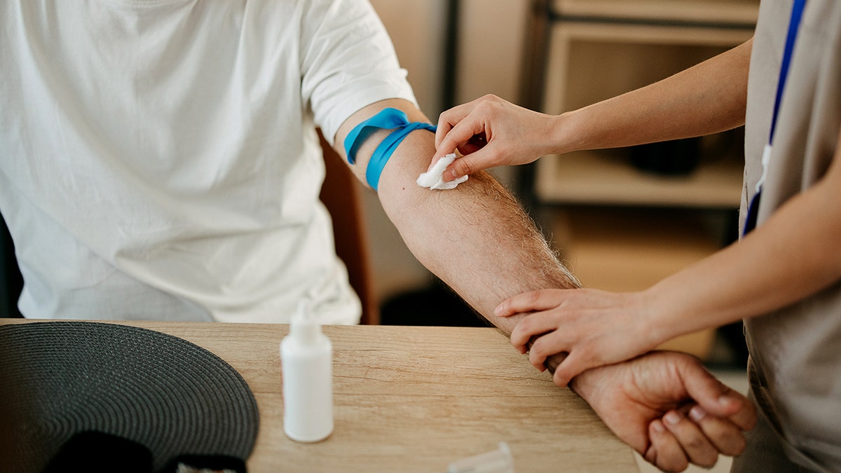 Nurse by drawing blood from an elderly man